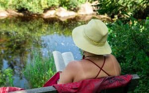 Woman reading a book outside by a pond. By Valmedia Creatives. Becoming healthier can seem intimidating, but these 10 easy, healthy actions to do regularly can make a world of difference. Image