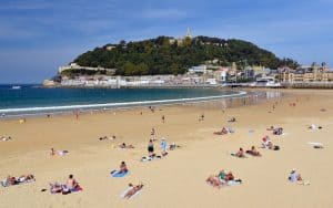 White chalet-style homes, the Pyrénées, golden beaches, a long promenade, and delicious foods – a few of the delights of San Sebastián. The golden sands of San Sebastián welcome visitors to the spirited Basque country. Image