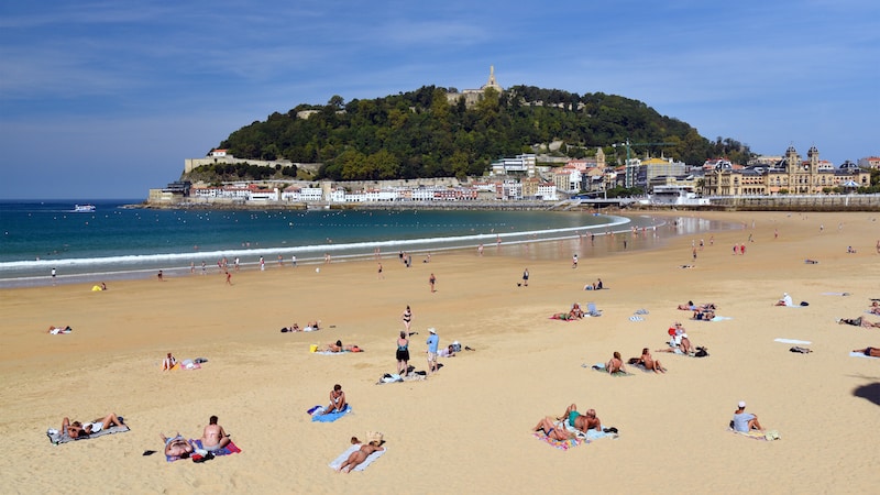 White chalet-style homes, the Pyrénées, golden beaches, a long promenade, and delicious foods – a few of the delights of San Sebastián. The golden sands of San Sebastián welcome visitors to the spirited Basque country. Image