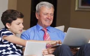 grandson and grandfather on tablet and laptop, possibly doing a puzzle like Jumble. By Sepy67 Image