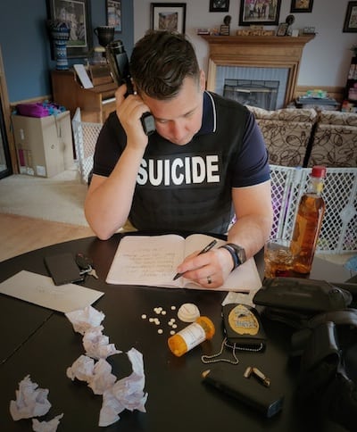 Depressed man on the phone, marked with suicide on his chest, using medications and alcohol to self medicate