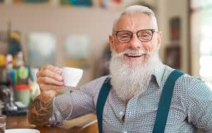 smiling middle-aged hipster man at a bar. By Alessandro Biascioli. Humorist Greg Schwem bemoans the dying art of face-to-face communication, a modern-day social “pandemic,” worsened by smartphone usage. Image