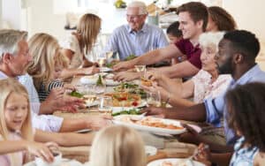 A large extended family around a dinner table. By Monkey Business Images. Poet and writer Cathy Hollister reflects on family gatherings and holiday celebrations – memorable events that serve up “comforts and jolts.” Image