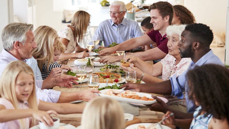 A large extended family around a dinner table. By Monkey Business Images. Poet and writer Cathy Hollister reflects on family gatherings and holiday celebrations – memorable events that serve up “comforts and jolts.” Image