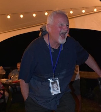 older man laughing at an outdoor event in a covered tent
