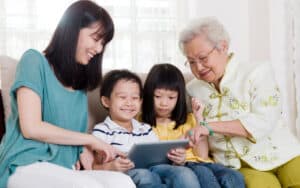 three generations, from grandmother to mom to two kids, playing on a tablet. Image by Wong Sze Yuen. Used for Jumble puzzle Image