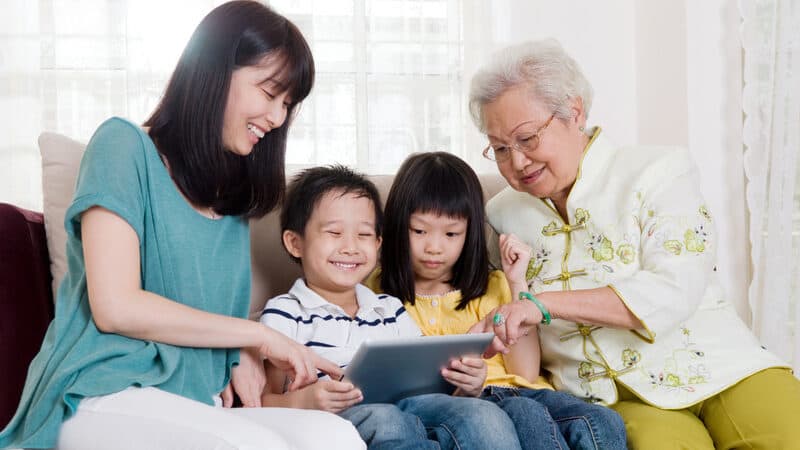 three generations, from grandmother to mom to two kids, playing on a tablet. Image by Wong Sze Yuen. Used for Jumble puzzle Image