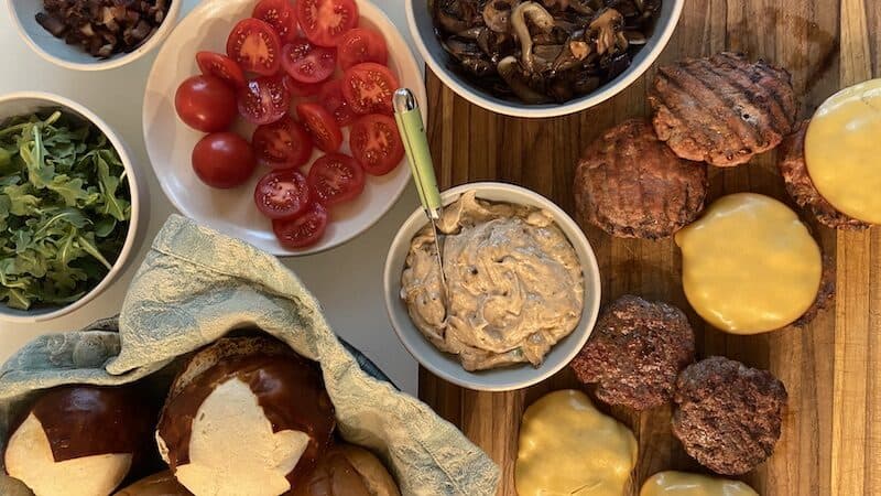 A burger buffet of burgers, tomatoes, toppings, buns, etc. This burger bar proves flexible when guest count fluctuates. Image