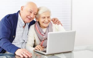 happy senior couple on laptop, from Robert Kneschke. A son wants to keep the family Zoom connection alive for his aging parents, but his siblings have lost interest. See what “Ask Amy” says. Image