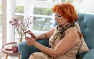 woman looking at a tablet, perhaps playing a puzzle. For this week's Boggle: go fish! Image