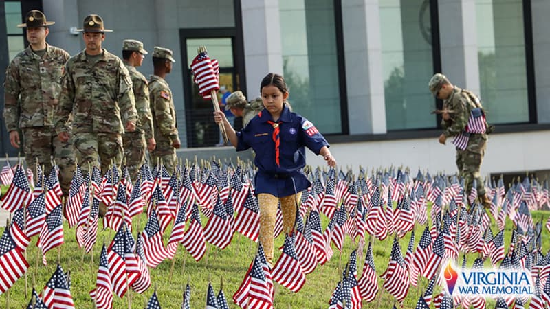 A volunteer planting small American flags on the Hill of Heroes at the Virginia War Memorial, Richmond. (For What's Booming: Heroes and Activists)