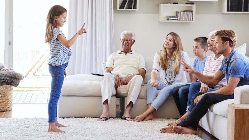 family playing charades for funny games for game night. Image by Monkey Business Images