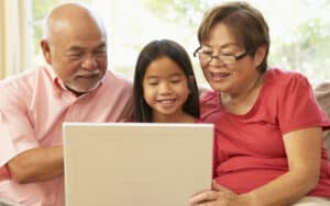 grandparents granddaughter on a laptop, from Monkey Business Images, perhaps playing a puzzle like the Jumble puzzles Image