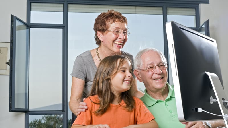 grandparents with their granddaughter looking at a computer monitor and smiling, by Noam Armonn. For Jumble puzzle with an ice rink.