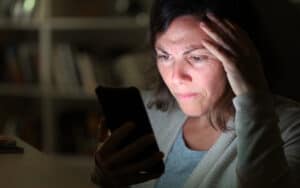agitated woman looking at cell phone at home in the evening, from Info723783. She’s dating at 45 and Facebook makes her feel like a kid, and not in a good way! See what Ask Amy says about social media and adult dating. Image