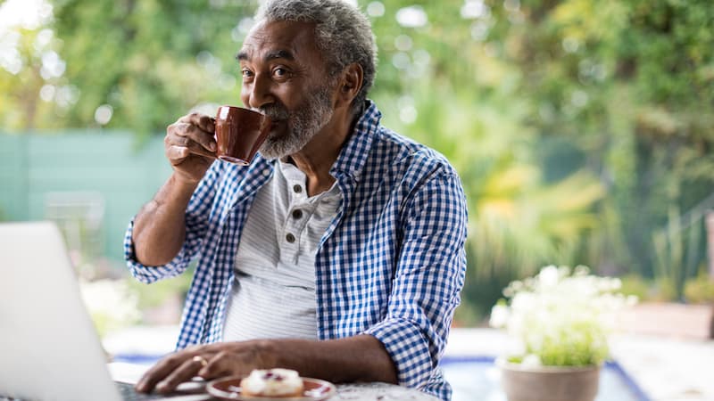 man on laptop with coffee, possibly doing puzzles or games. From Wavebreakmedia