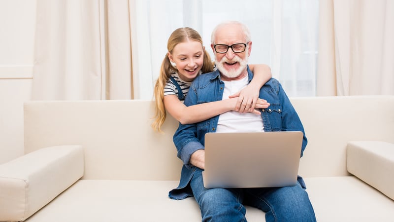 a granddaughter and granddad smiling at a laptop monitor, for Jumble puzzles for kids and adults