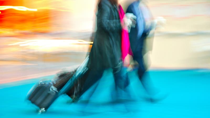 airport rushing people pulling suitcases, by Karin Hildebrand Lau. His procrastinating wife misses flights for their travels. They’ve missed planes and left the luggage in the car. See what “Ask Amy” advises.