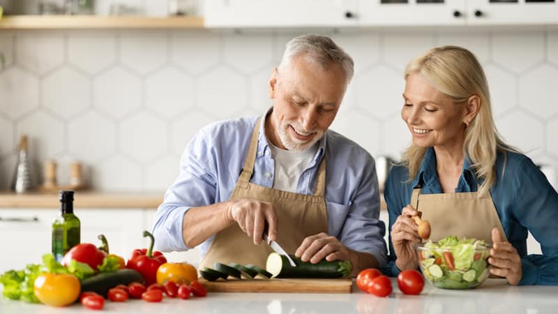 couple fixing salad, image by Prostockstudio. For article on how to save on healthy food.