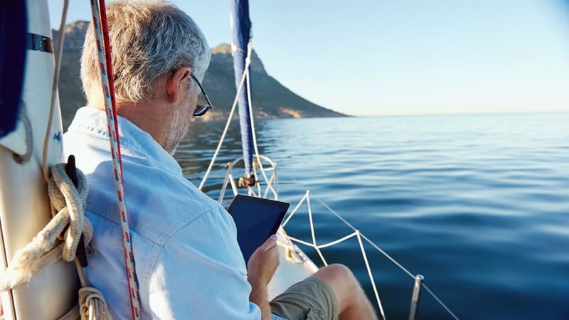 man with tablet on sailboat Warrengoldswain. Used for Boggle puzzle, "find the fish"