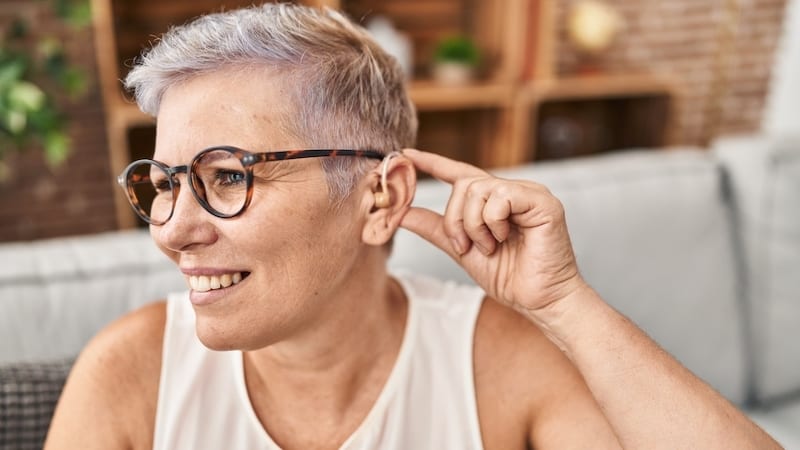 smiling middle aged woman with hearing aids, image by Aaron Amat. for article on over-the-counter hearing aids