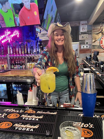 Bartender presenting a cocktail at Great American Ranch bar.