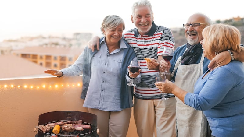 Two older couples laughing and toasting friendship on a porch overlooking mountainside. By Alessandro Biascioli. For article on overcoming negative thinking patterns.