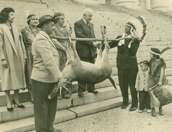 An Indigenous chief presents a deer to the Virginia governor on the steps of the Capitol. Governor Albertis S. Harrison, who served from 1962 to 1966, receives the annual tribute from Virginia’s tribes at the State Capitol. This Thanksgiving tradition has been observed for more than 300 years