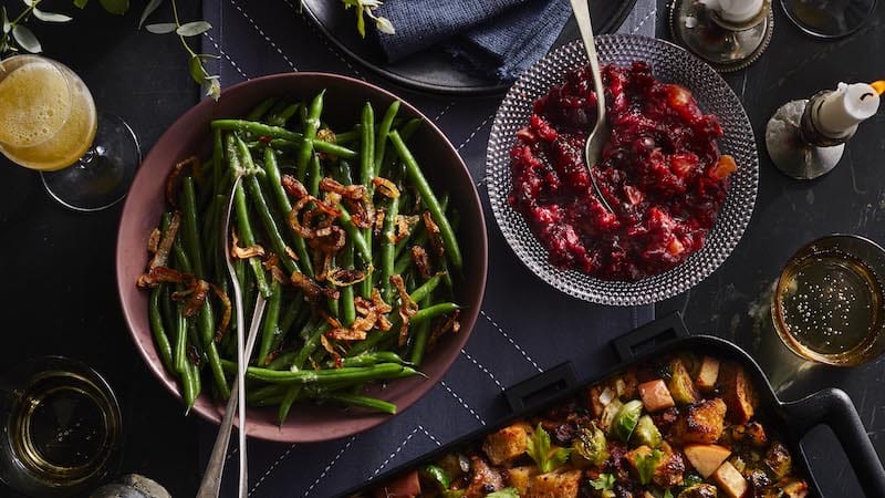 steamed green beans on a holiday table with cranberries and sweet potatoes