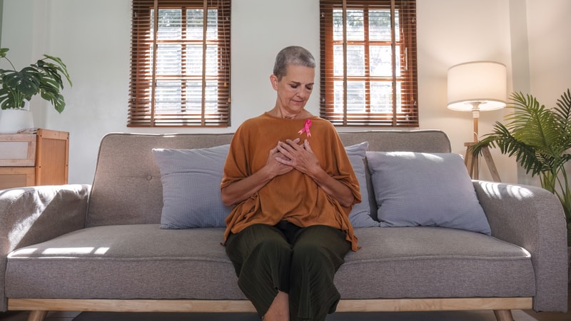 female cancer survivor on her sofa at home, for article on managing unwanted weight loss compliments. Image by Wichayada Sunwannachun