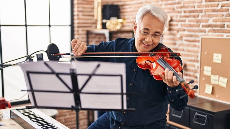 A senior man learning to play a violin