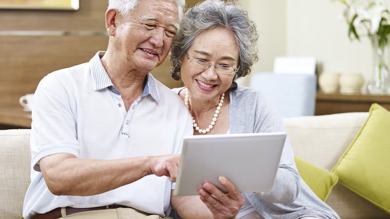 An Asian couple looking at a computer tablet. By Imtmphoto.