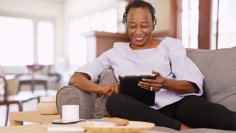 woman using a tablet, perhaps to do puzzles like Boggle Puzzle: Find Eight Relatives