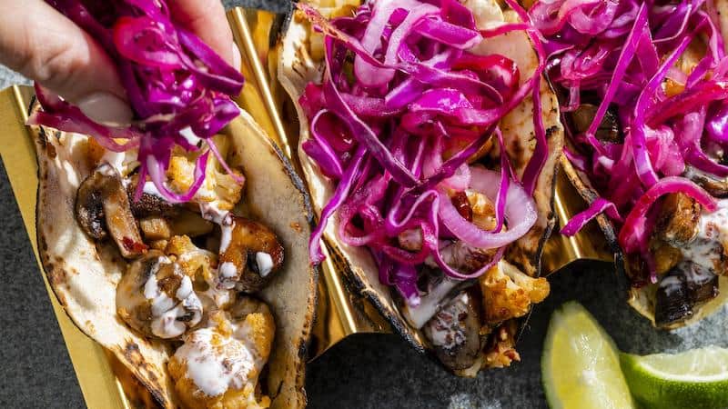 Chipotle mushroom and cauliflower tacos, from America's Test Kitchen. Warm, smoky mushrooms, roasted cauliflower, cool crema, and crunchy cabbage come together in this delicious dish.