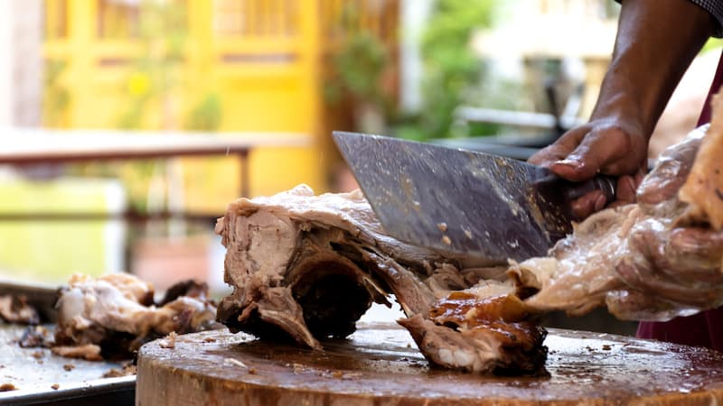 A man cutting barbecued ribs with a large meat cleaver. By Ratchapon Supprasert. Used in What's Booming, January 18+