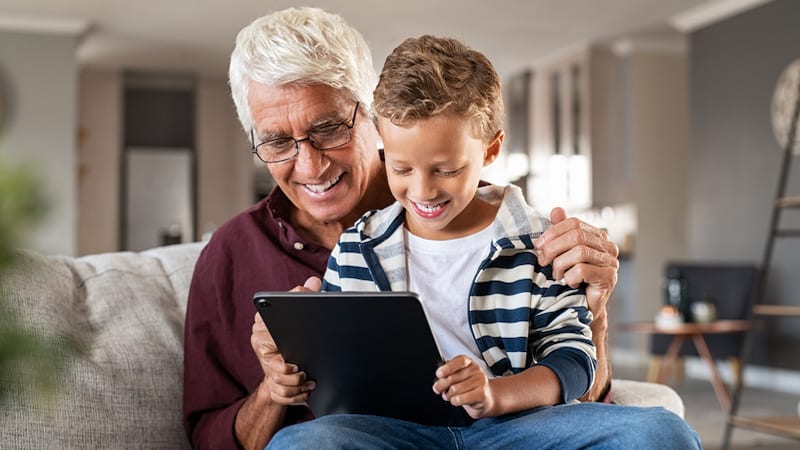 Granddad and grandson on a computer tablet, possibly doing puzzles or games