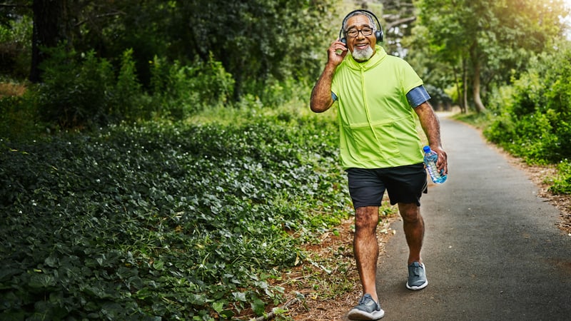 A man on a walk in nature, wearing headphones. By Yuri Arcurs. Article: Tips for Keeping Resolutions