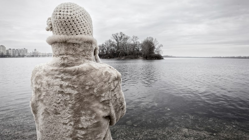 A woman looking out over a lake on a gray, sad winter day. Image by Karayuschij. Article on question of whether you can treat SAD with food