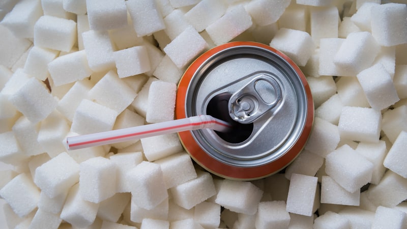 A soda can with a straw surrounded by sugar cubes, by Vchalup. For article on why and how to quit drinking soda.