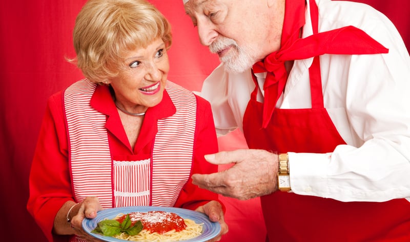 A chef and woman in stylish red aprons. We look at the connection between adventures and on-demand clothing, creating a delightful fusion of taste and style: flavorful fashion. Image by Lisa F. Young