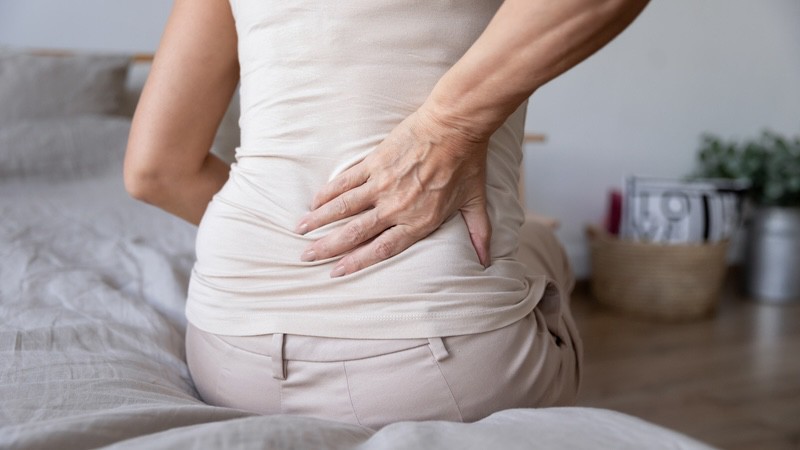 woman having back pain, by Fizkes, for article on pain management