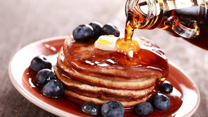 Bourbon maple syrup pouring over blueberries and pancakes. Image by Mk74