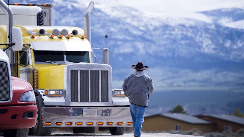 A trucker in front of his semi tractor truck, parked in front of snow covered mountains. Image by Vitpho. Article: An Attitude of Gratitude: My Tipping Point