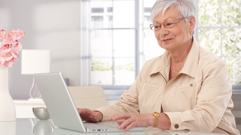 A cheerful woman on a laptop, perhaps playing an online puzzle or game, like Sudoku or Jumble. Image by Nyul. For Boggle music puzzle