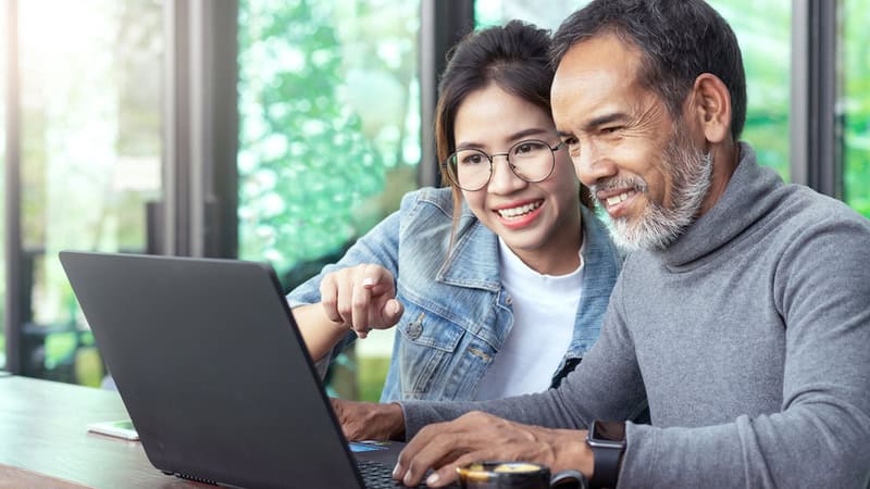 two adults on laptop, possibly doing a puzzle online, like the Boggle puzzle or Jumbles puzzles from Boomer magazine. Teeraphat Sirisatonpun