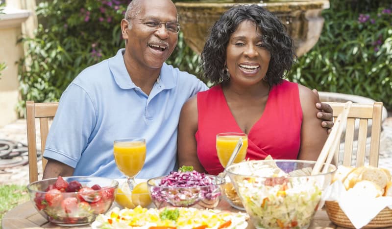 Happy couple sitting outside for a meal, choosing foods to maximize memory. Image by Spotmatik