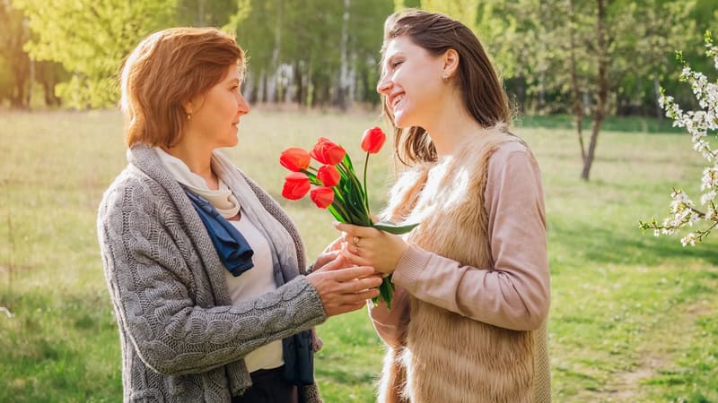 Young woman giving her mother some tulips. By Mario Boiko. Used with What's Booming May 9 to 16, including Mother's Day