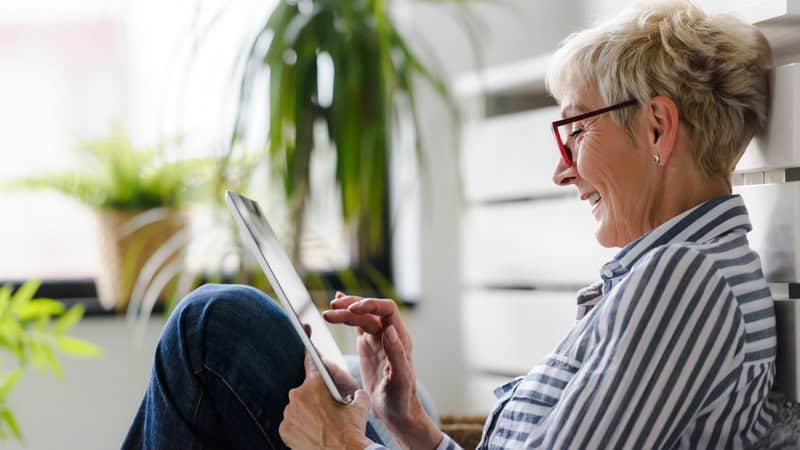 Woman smiling looking at her tablet, perhaps playing a puzzle like this week's Boggle Find Six States. Image by Lordn7