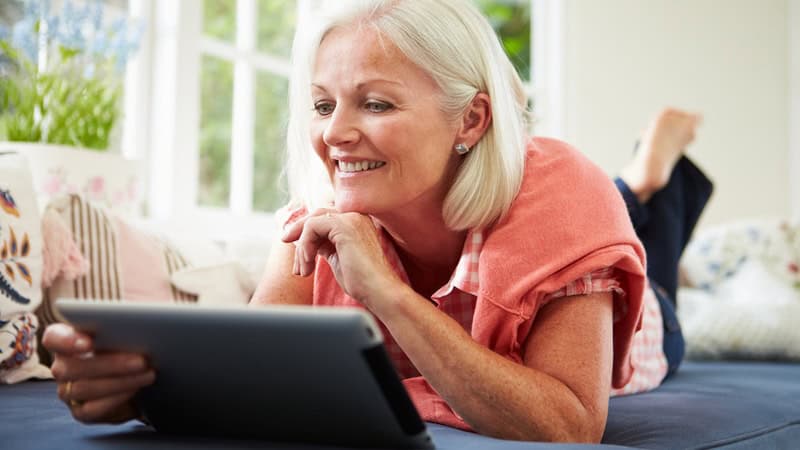 Woman using a tablet, possibly playing the Boggle word search puzzle, finding words ending in LF