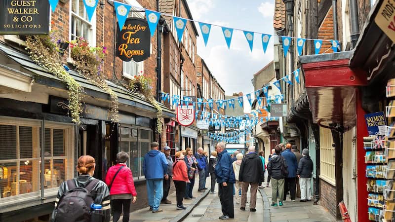 A city street through York in England: York’s atmospheric old butchers’ quarter, The Shambles, hosts tipsy medieval buildings. Though the lane looks tidy today, the blood, guts, and waste flushed into its center channel was once truly a shambles. CREDIT: (Dominic Arizona Bonuccelli, Rick Steves’ Europe).